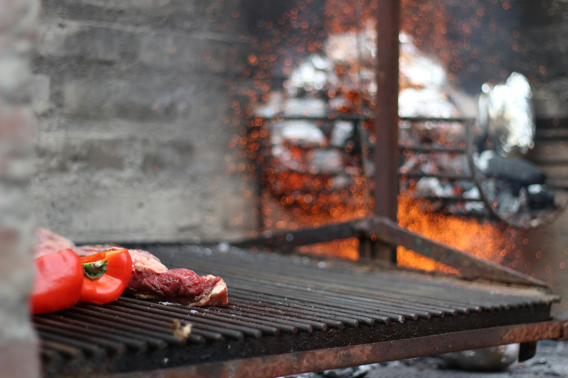 Мясо и перец на решётке parrilla на фоне открытого огня