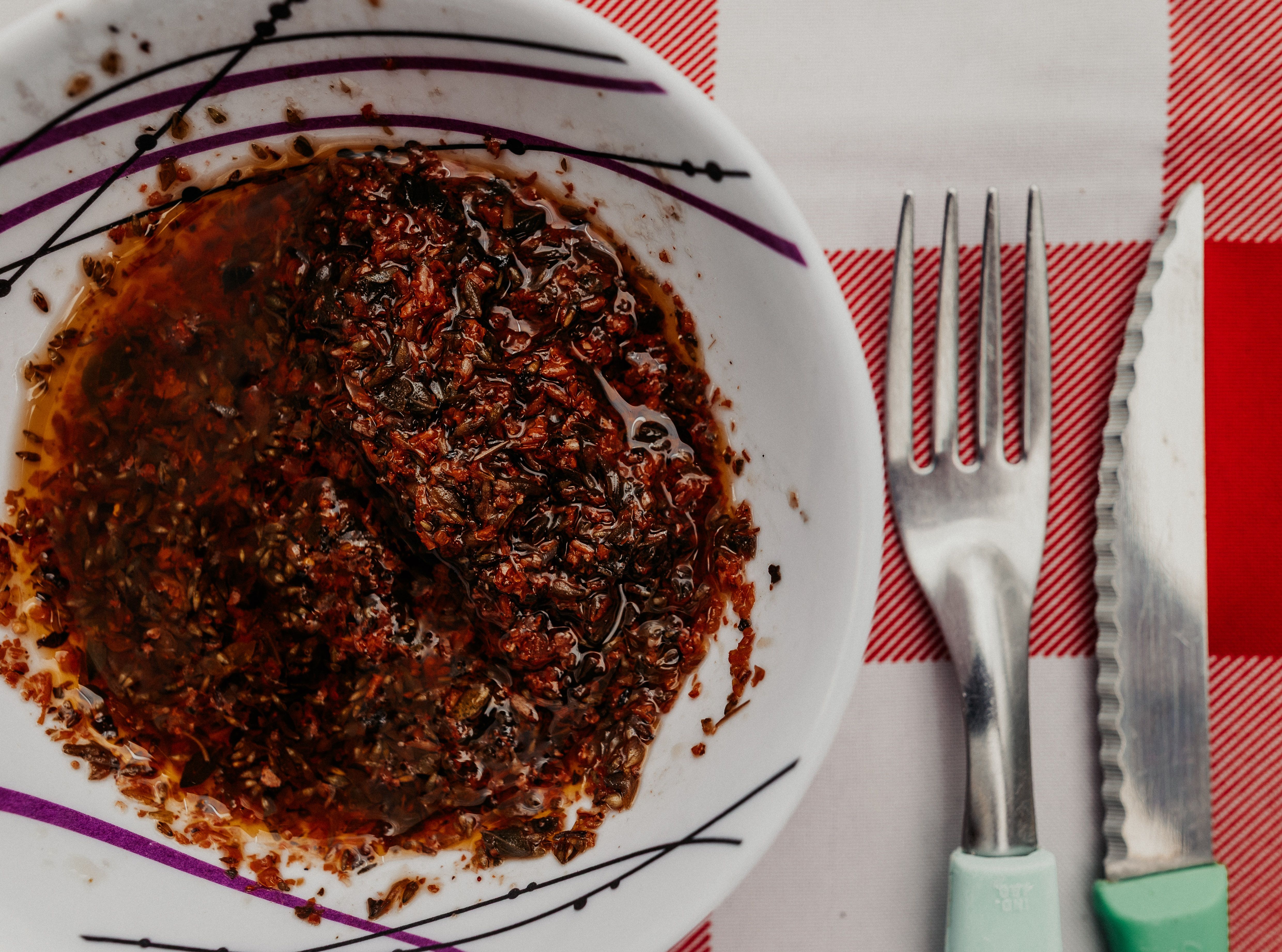 Соус chimichurri в тарелке рядом с вилкой и ножом